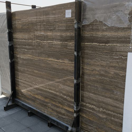 High-quality brown travertine slab showing warm earthy tones, rich walnut colors, and a natural porous texture.