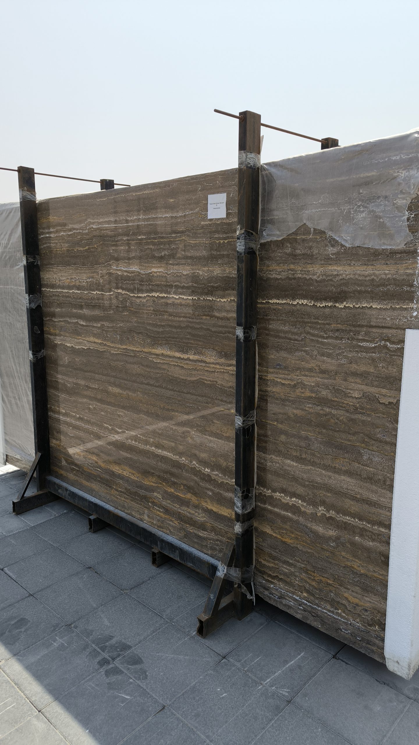 High-quality brown travertine slab showing warm earthy tones, rich walnut colors, and a natural porous texture.